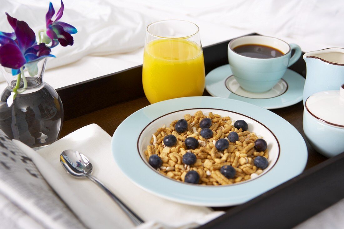 Frühstück im Bett mit Müsli, Orangensaft und Kaffee
