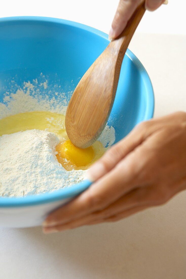 Aufgeschlagenes Ei und Mehl in Schüssel vermischen