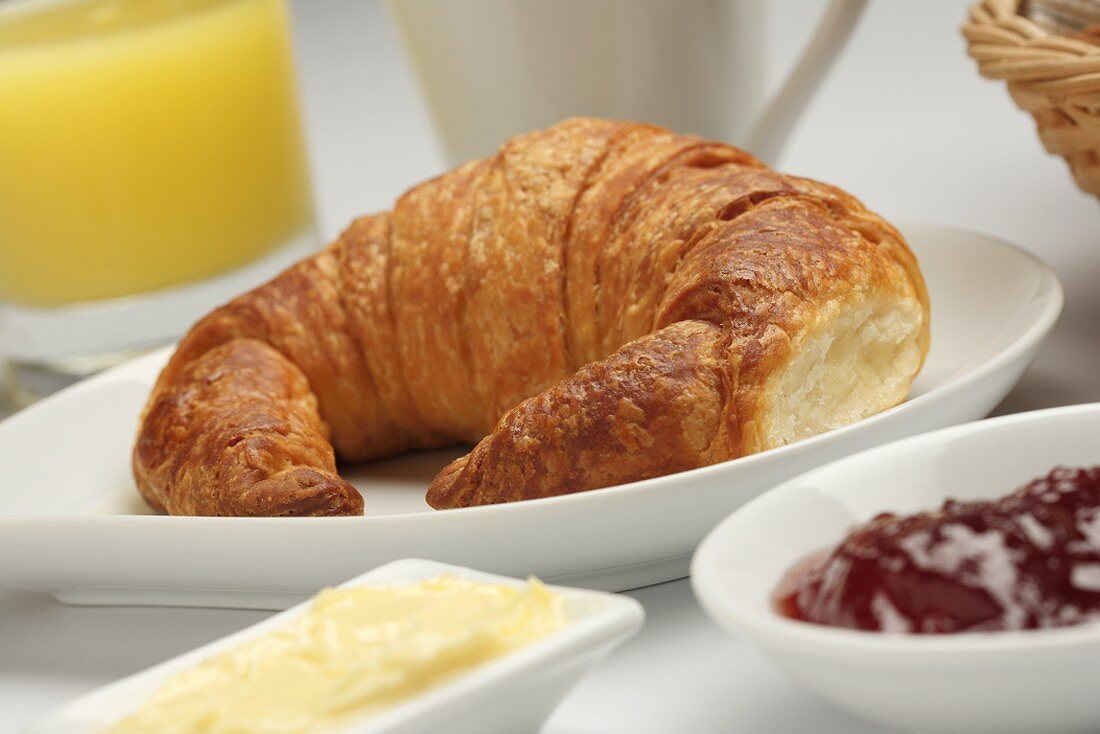 Croissant, Butter und Marmelade zum Frühstück