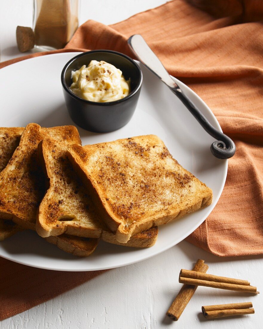 Zimttoasts und Schälchen mit Zimt-Honig-Butter auf Teller
