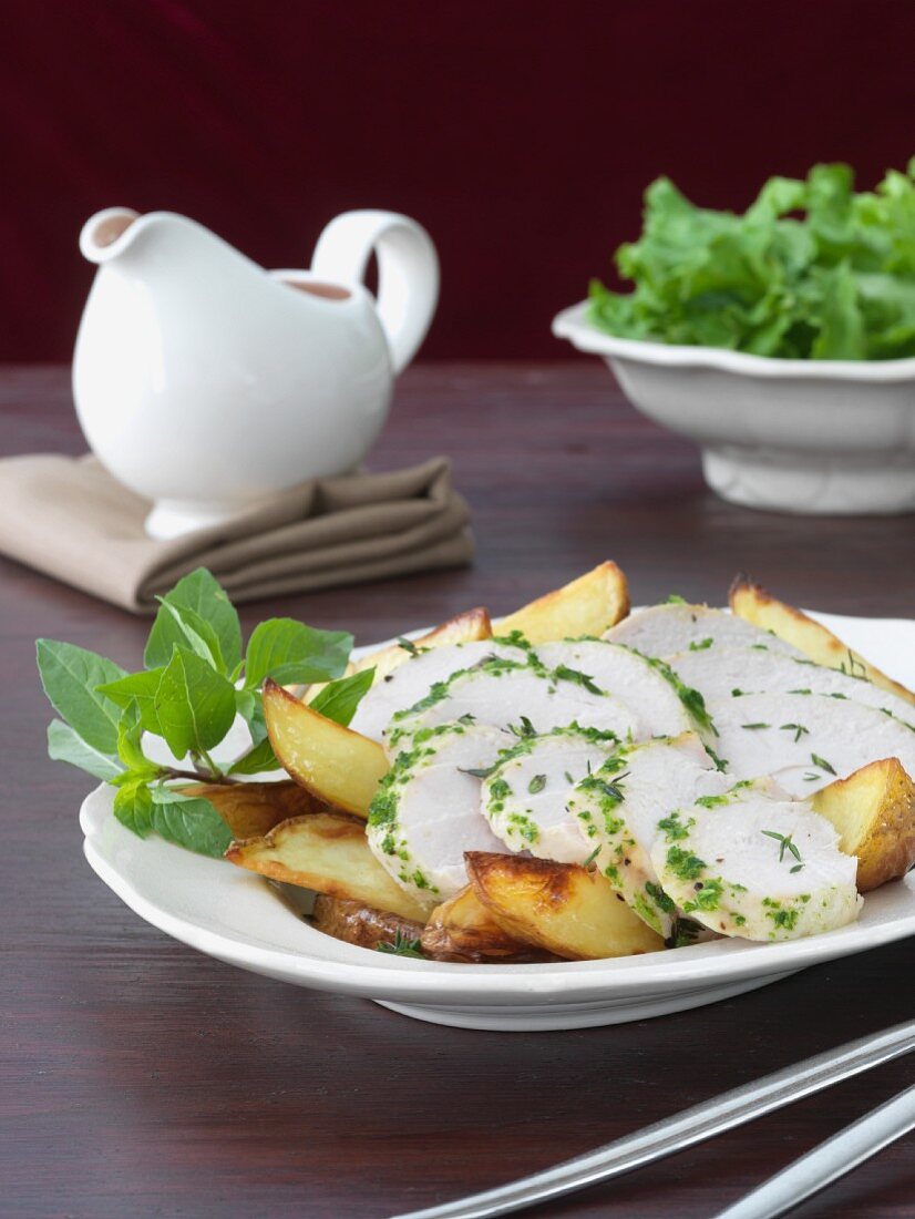 Sliced Herbed Chicken Over Oven Roasted Potatoes in a Serving Dish