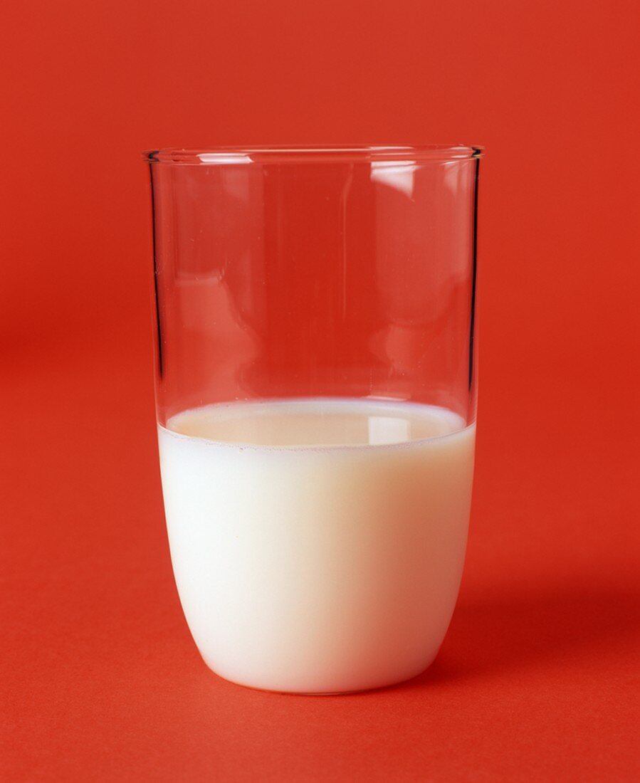 Glas Milch auf orangefarbenem Untergrund