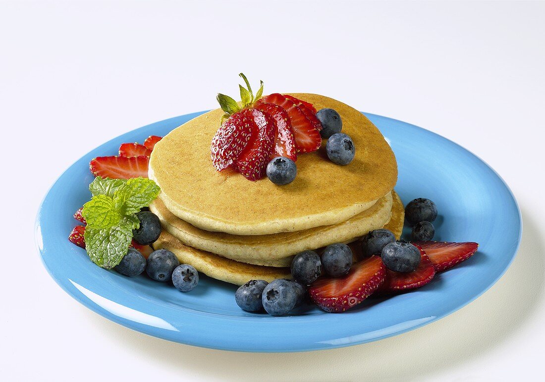 Pancakes mit frischen Beeren auf blauem Teller