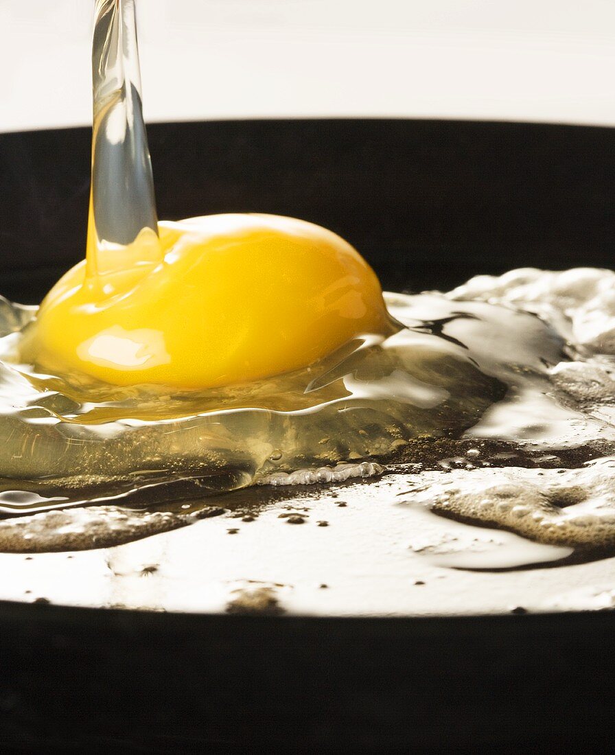 Spiegelei zubereiten: Ei in eine Pfanne aufschlagen