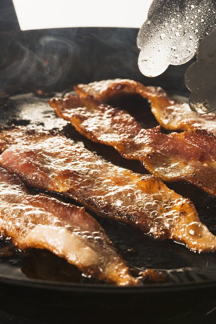 Bacon being fried in a pan