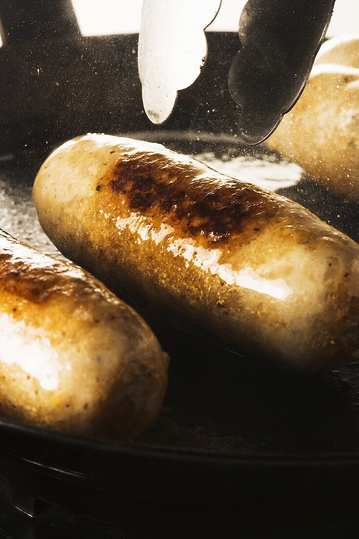 Sausages being fried in a pan