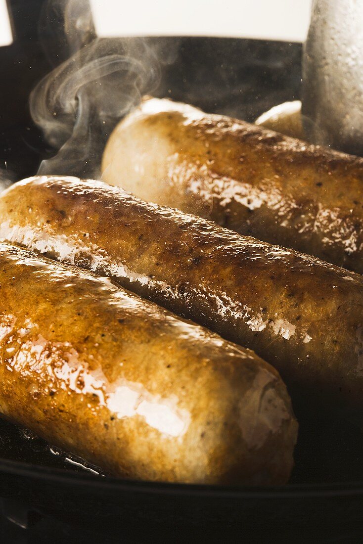 Sausages being fried in a pan
