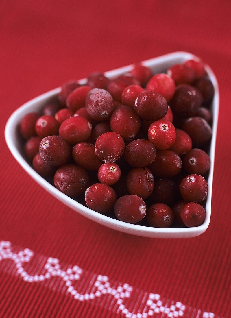 Cranberries in white bowl on red tablecloth