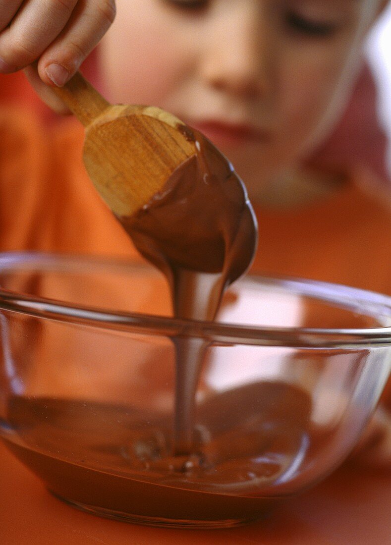 Kleines Mädchen rührt Schokocreme mit Holzlöffel