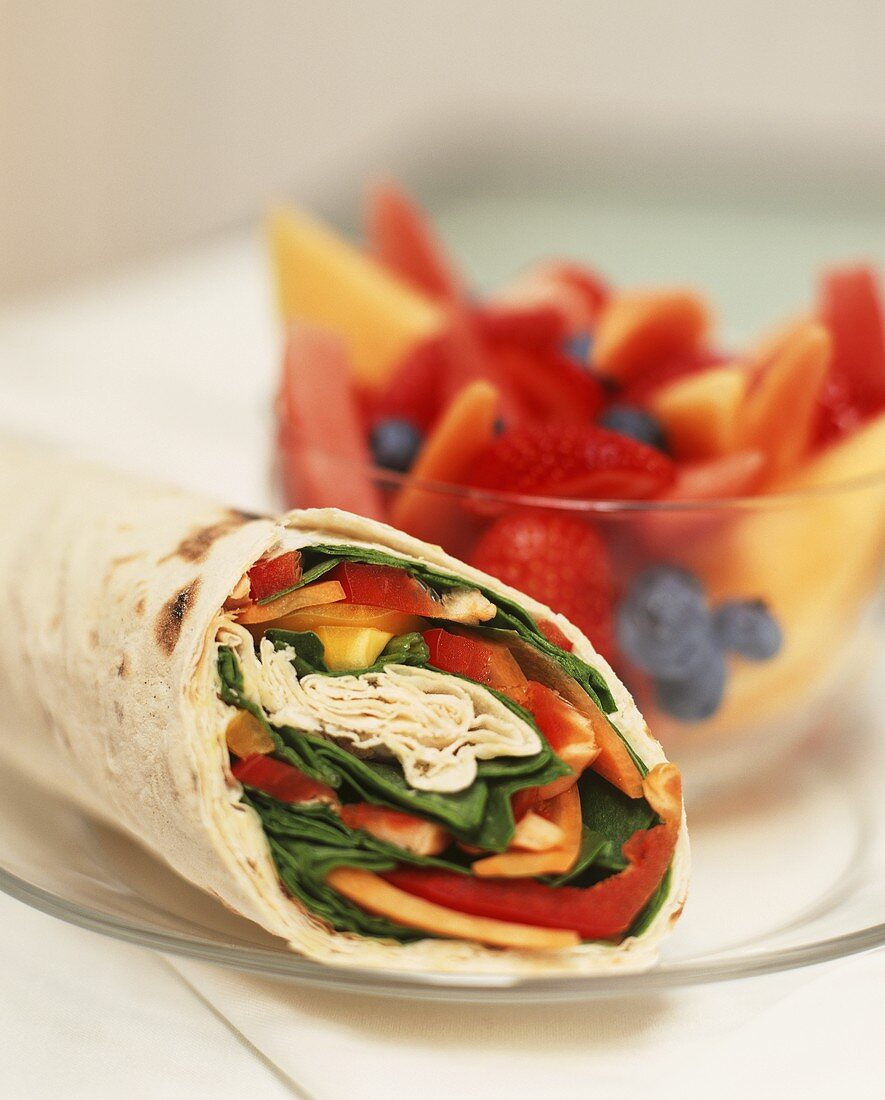 Wrap with vegetable filling, fruit salad behind