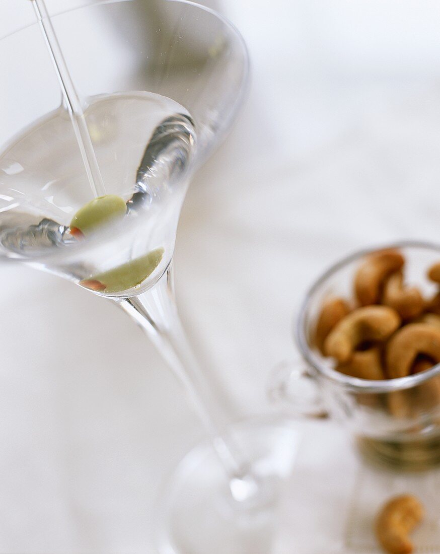 Martini mit grüner Olive und Cashewkernen