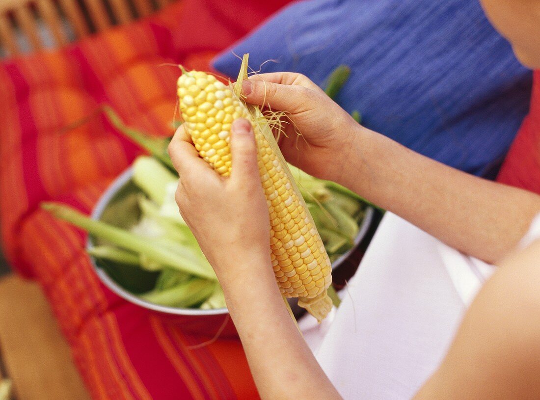 Woman removing the husks from corncob