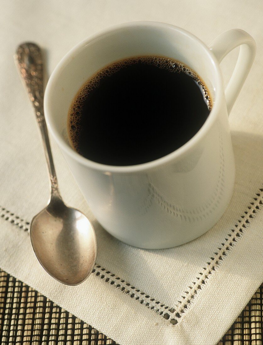 Schwarzer Kaffee in weisser Tasse, daneben Löffel