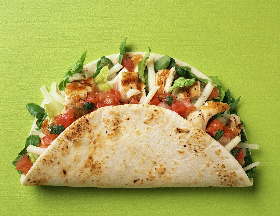 Taco shell with chicken, tomatoes, cheese and lettuce