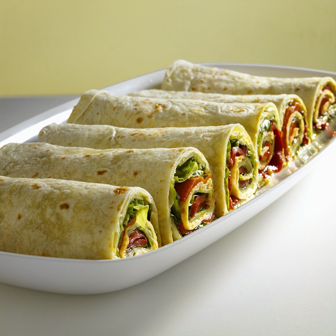 Six wraps filled with hummus and vegetables