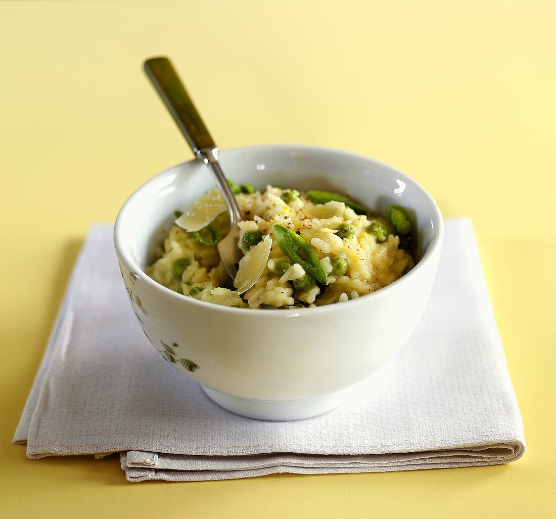 Risotto mit Erbsen und Parmesan in weißem Schälchen