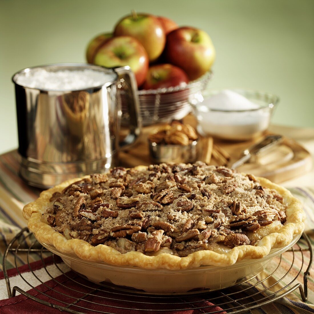 Whole apple & pecan pie; baking ingredients in background