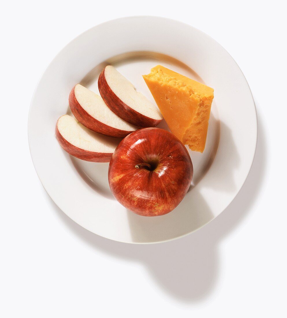 Roter Apfel, Apfelschnitze und Stück Cheddar auf Teller