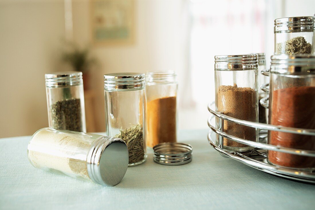 Spices in Glass Jars on a Table and in a Spice Rack