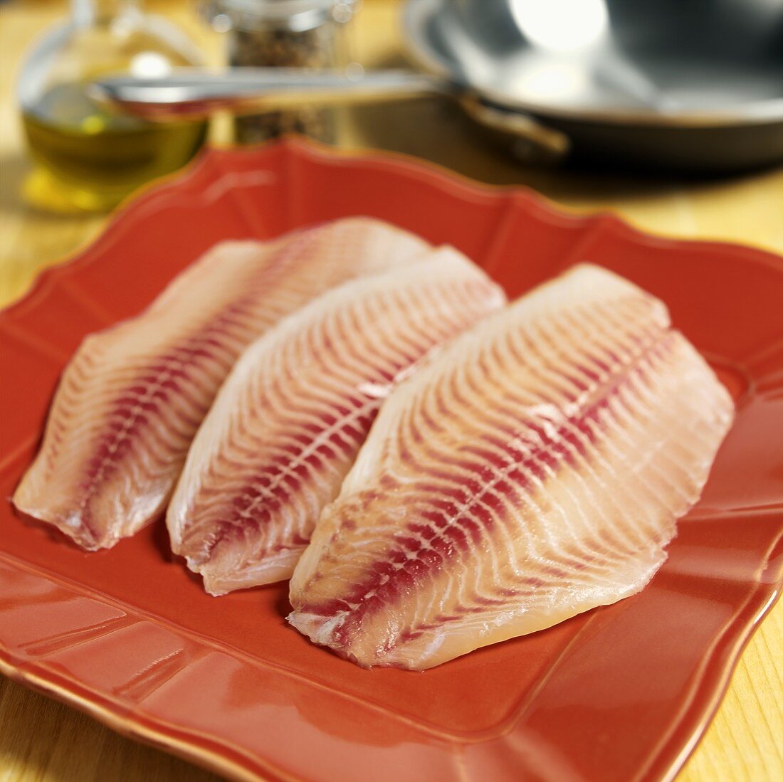 Fresh tilapia fillets on red plate