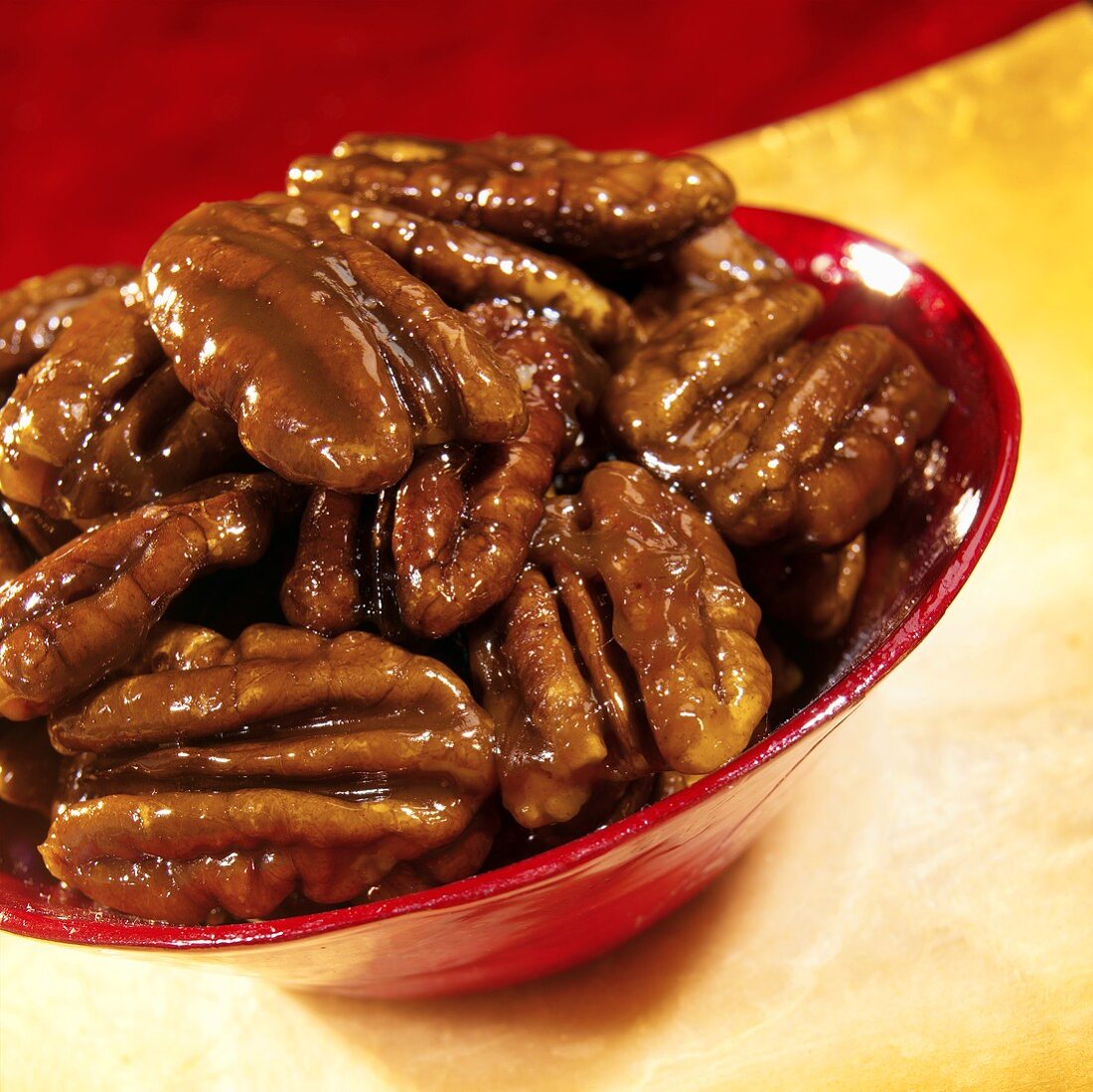 Caramelised pecan nuts in a red bowl