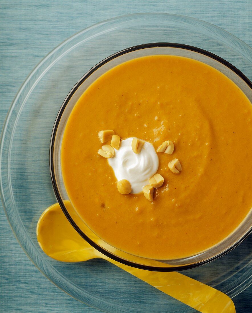 A Bowl of Creamy Carrot Soup with Peanuts and Sour Cream Garnish