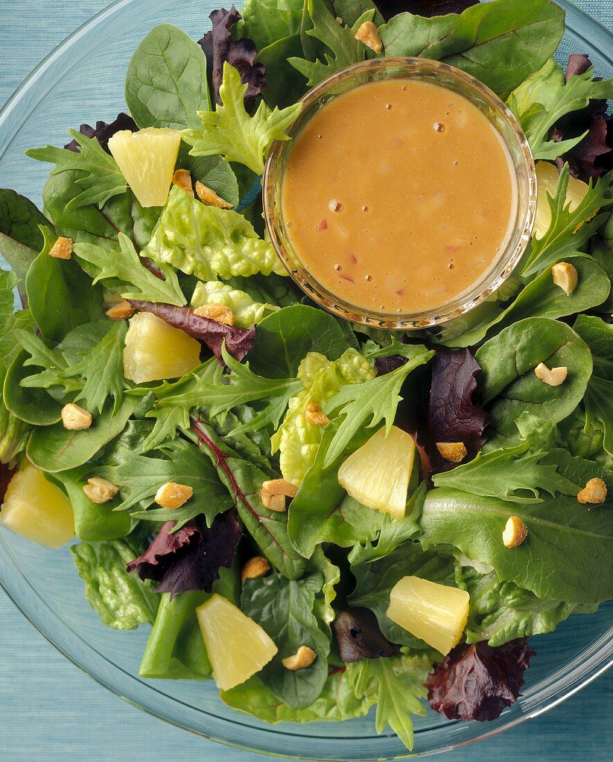 A Mixed Green Salad with Pineapple, Nuts and Salad Dressing