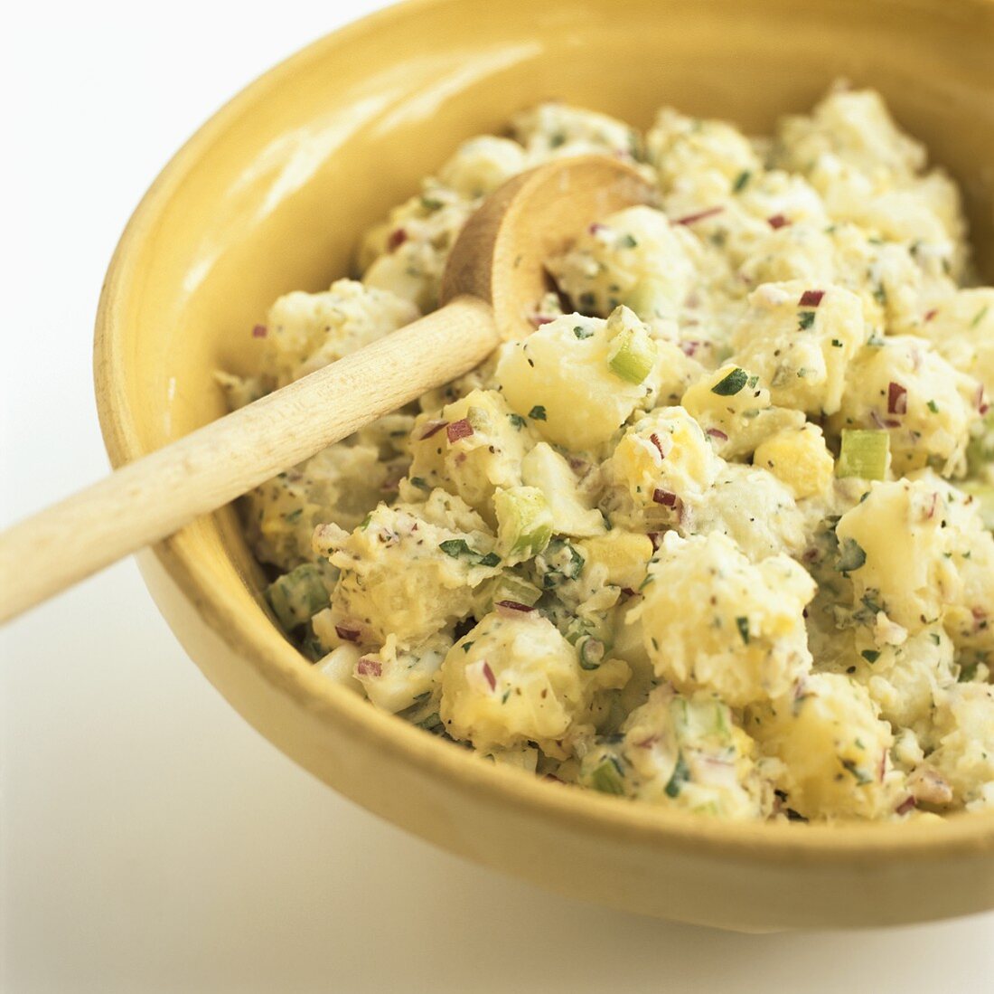 A Bowl of Potato Salad with a Wooden Spoon
