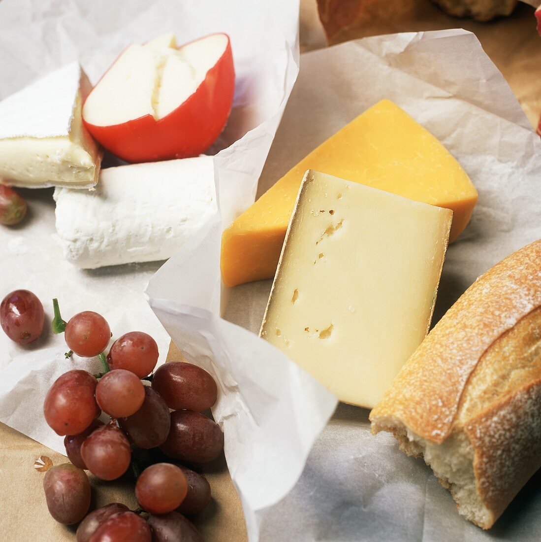 Verschiedene Käsesorten mit Baguette und roten Trauben