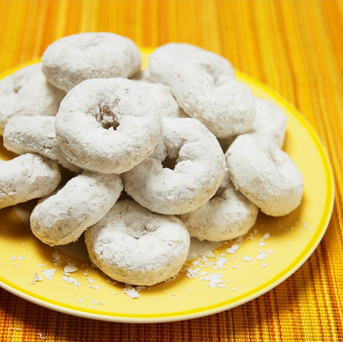 Doughnuts mit Puderzucker auf gelbem Teller