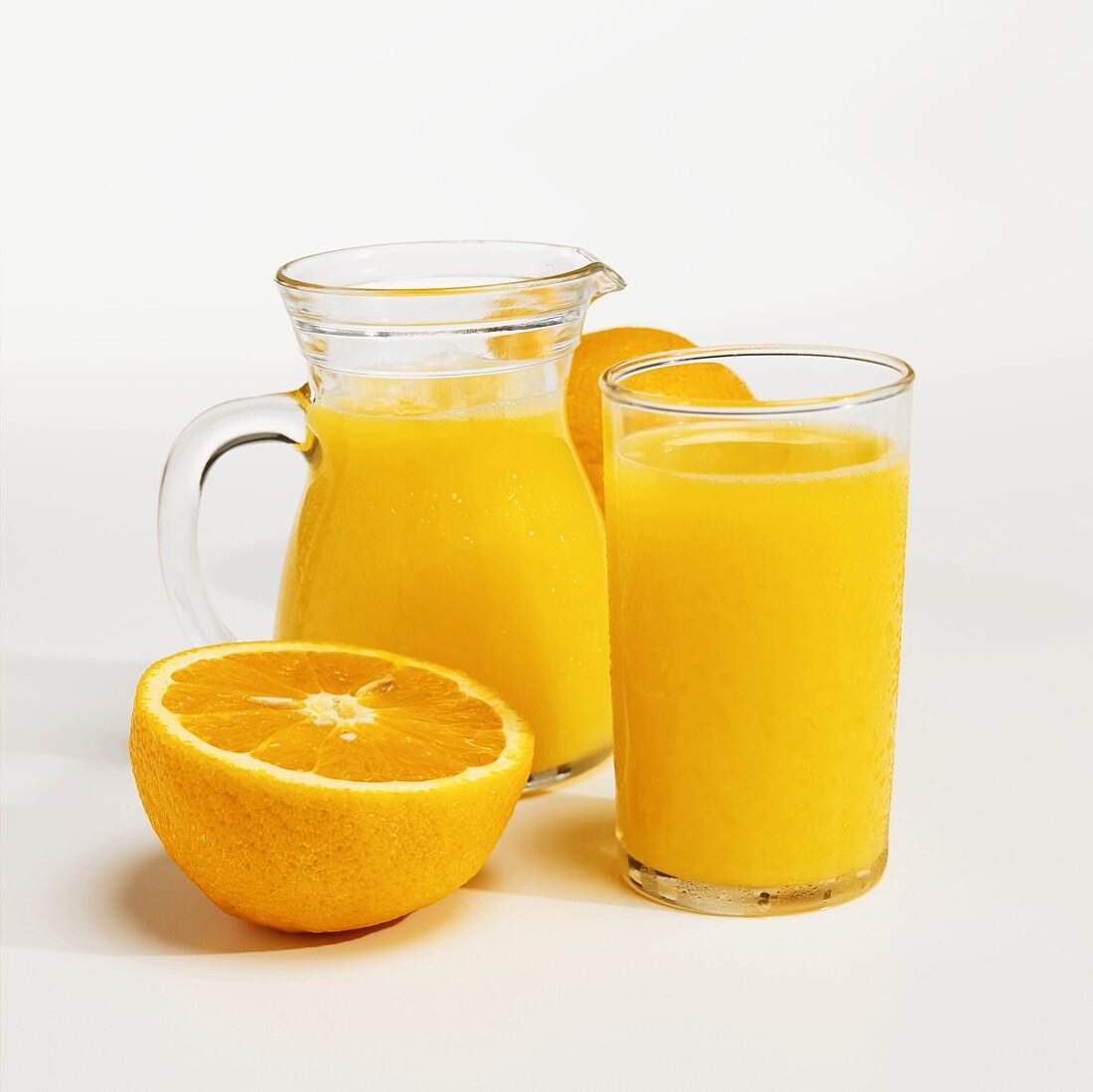 Orangensaft im Glas und Krug und frische Orange