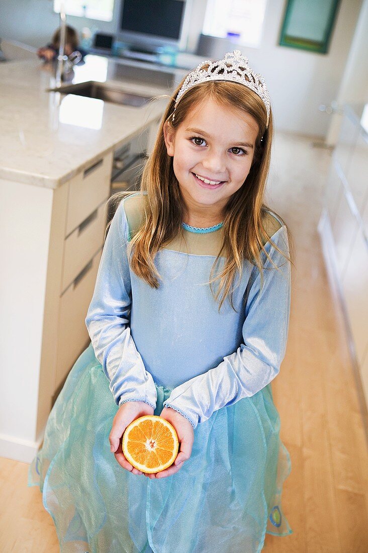 Kleines Mädchen, als Prinzessin verkleidet, hält Orange
