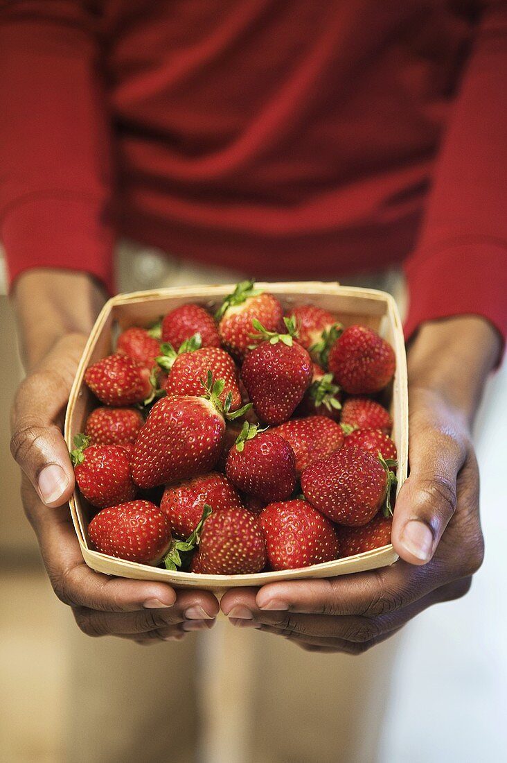 Hands Holding a Container of Strawberries