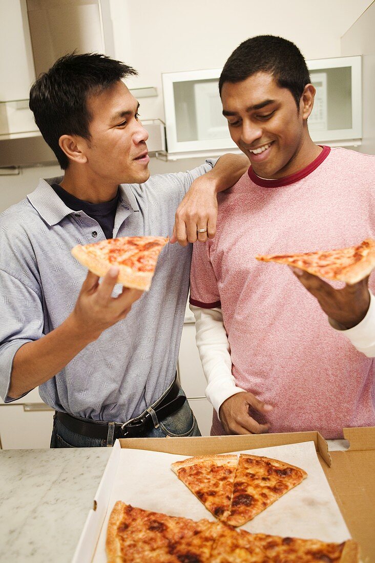 Zwei Freunde essen Pizza in der Küche