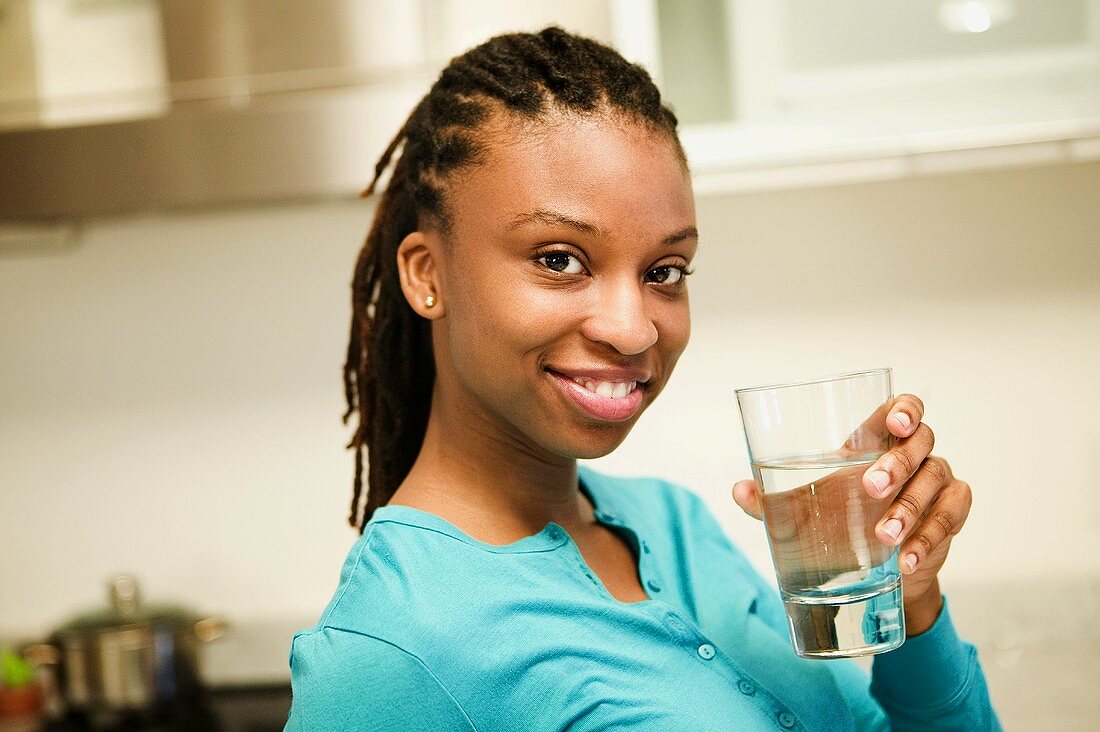 Lächelnde junge Frau hält Glas Wasser