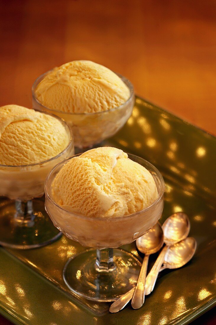 Three Glass Dishes of Vanilla Ice Cream on a Tray with Spoons