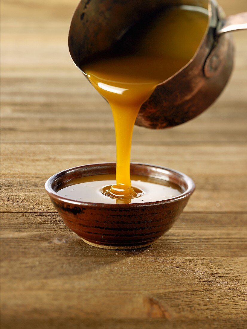Pouring caramel sauce from a saucepan into a bowl