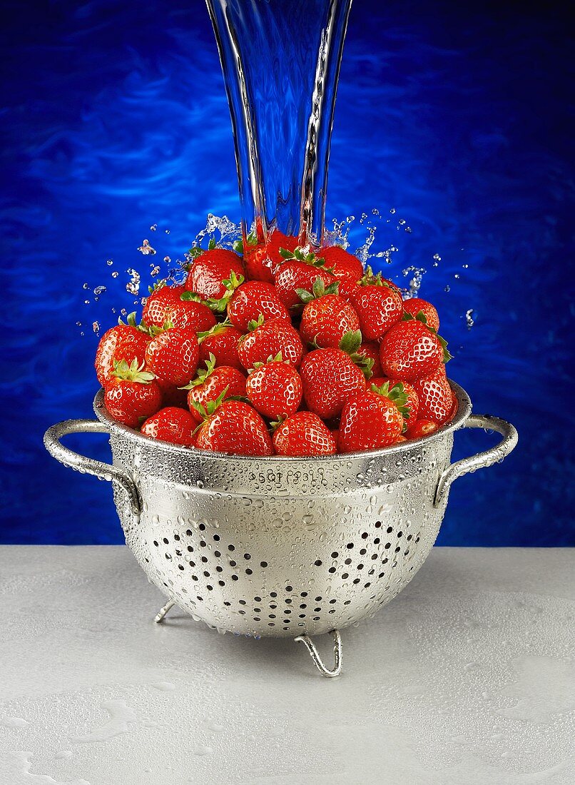 Erdbeeren im Abtropfsieb mit Wasser begiessen
