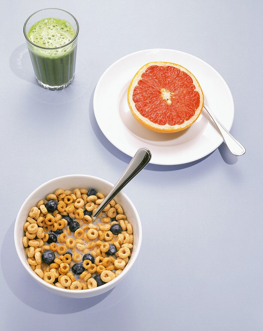 A Bowl of Oat Cereal with Blueberries, a Grapefruit Half and a Spirulina Fruit Smoothie