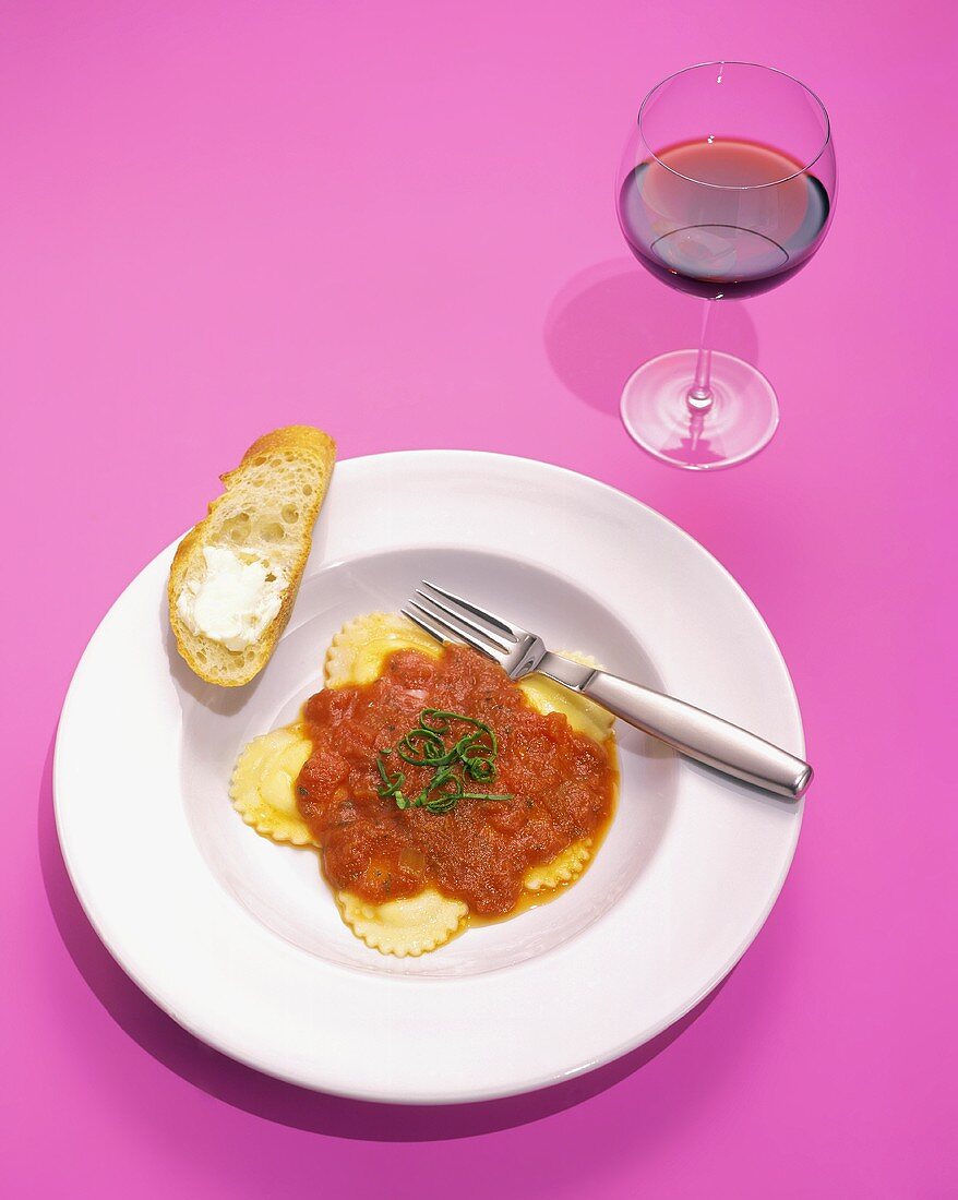 Ravioli mit Tomatensauce, Butterbrot und Glas Rotwein