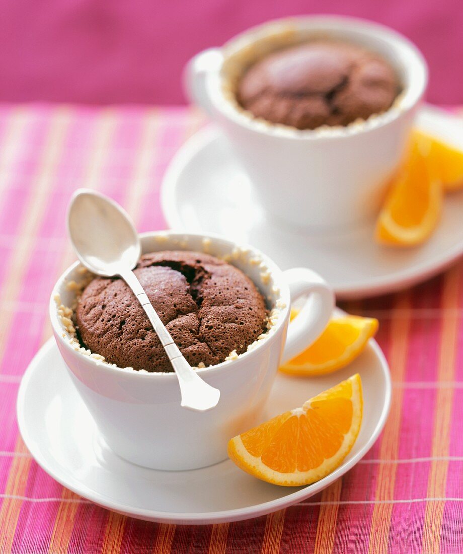 Schokoladenküchlein in Tassen mit Orangenschnitzen