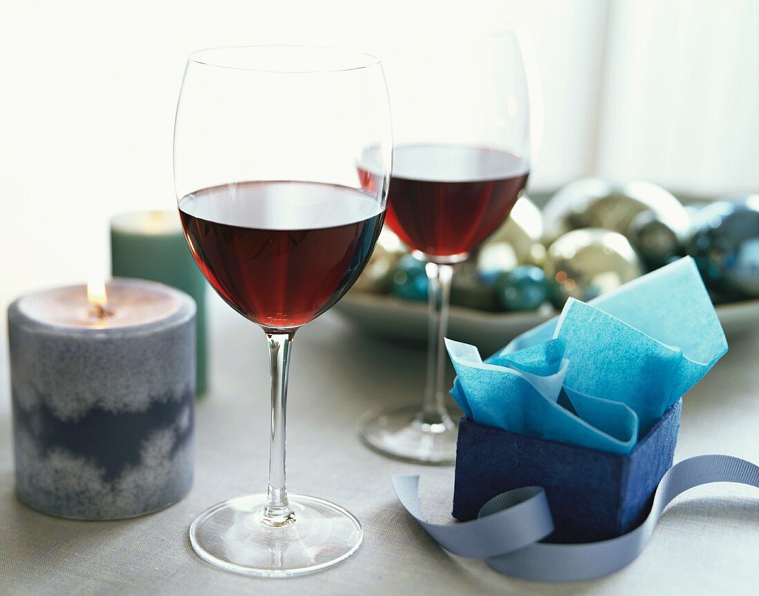 Zwei Gläser Rotwein, umgeben von Weihnachtsdeko
