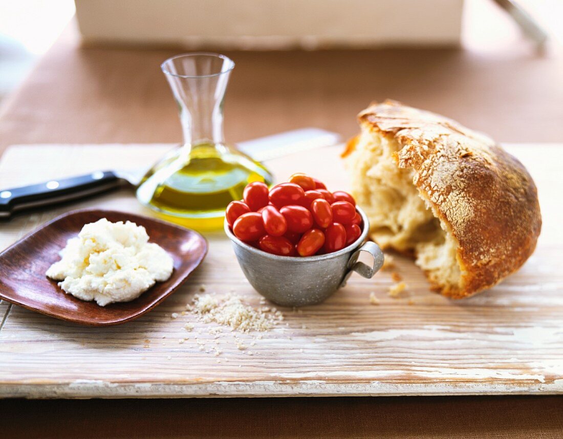 Stillleben mit Brot, Kirschtomaten, Olivenöl und Ricotta