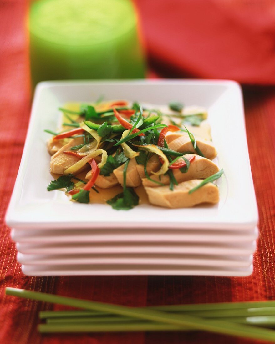 Stir Fried Chicken with Vegetables and Fresh Coriander on a Stack of Square White Plates