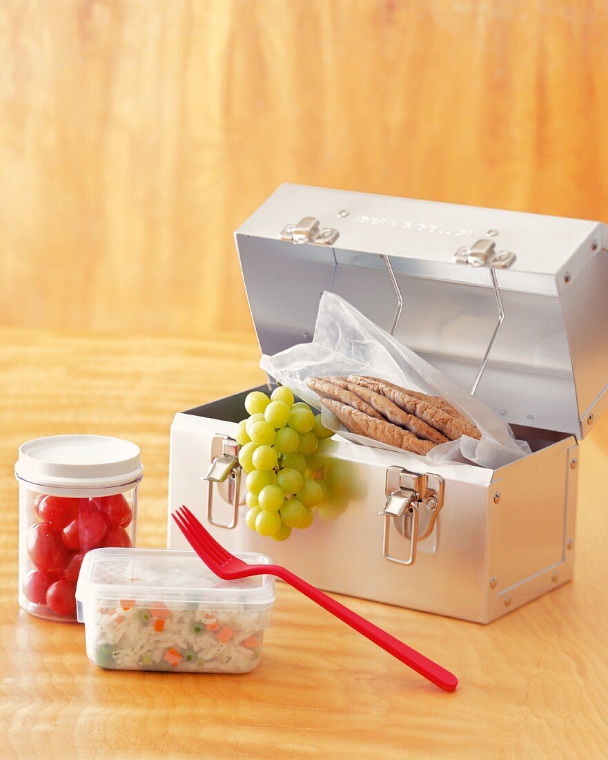 Lunchbox mit Trauben und Pitabrot, Reissalat und Tomaten