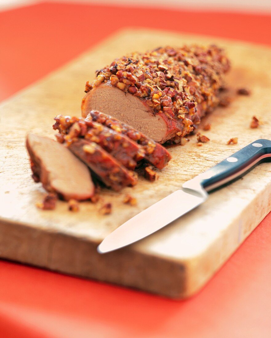 Pecan Encrusted Pork Loin with Knife on a Wooden Board