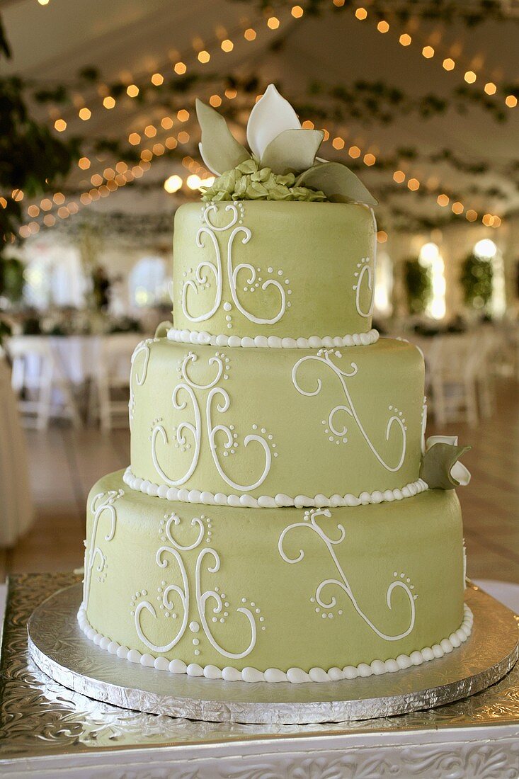 A Three Tier Wedding Cake with Green Fondant in a Reception Hall