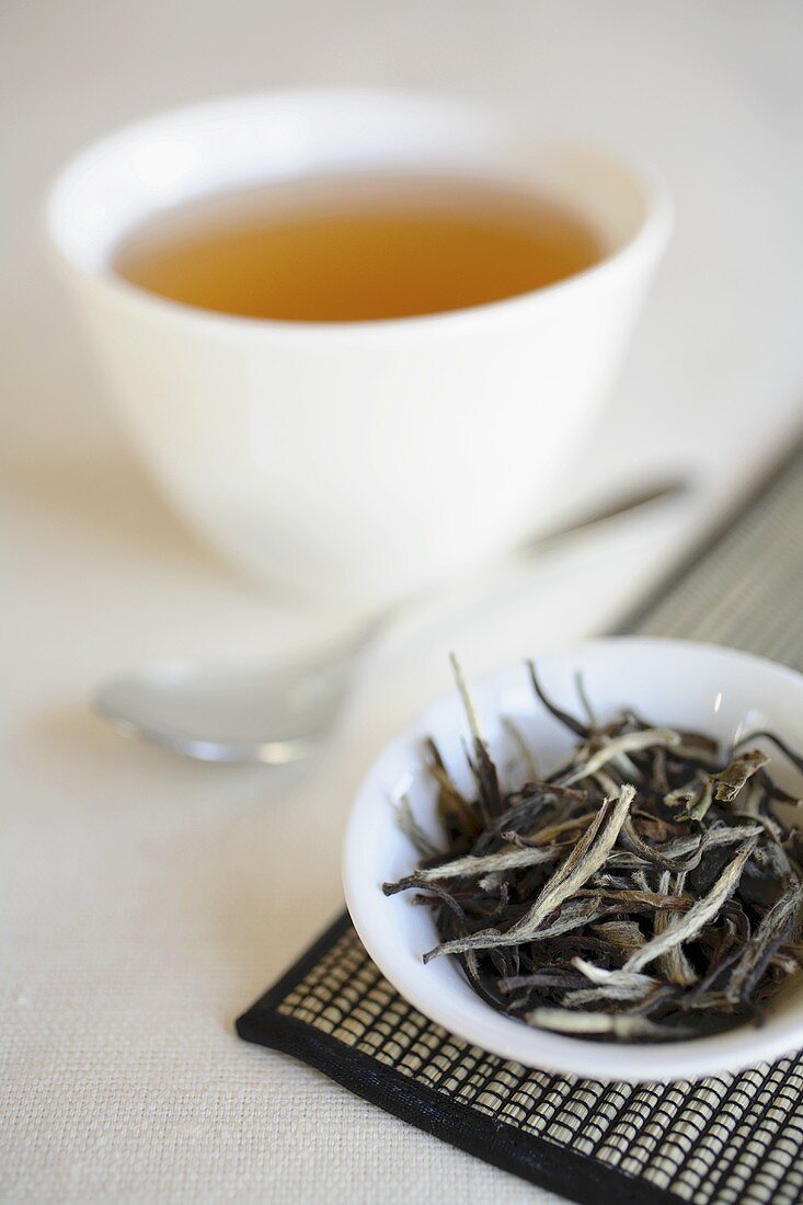 Weisser Tee (ungekocht) vor Schale Tee