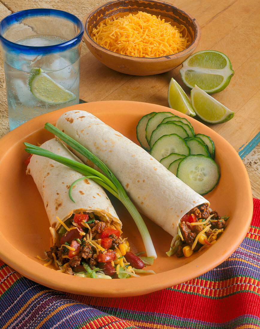 Two Beef and Bean Burritos with Seltzer and Lime and Shredded Cheese
