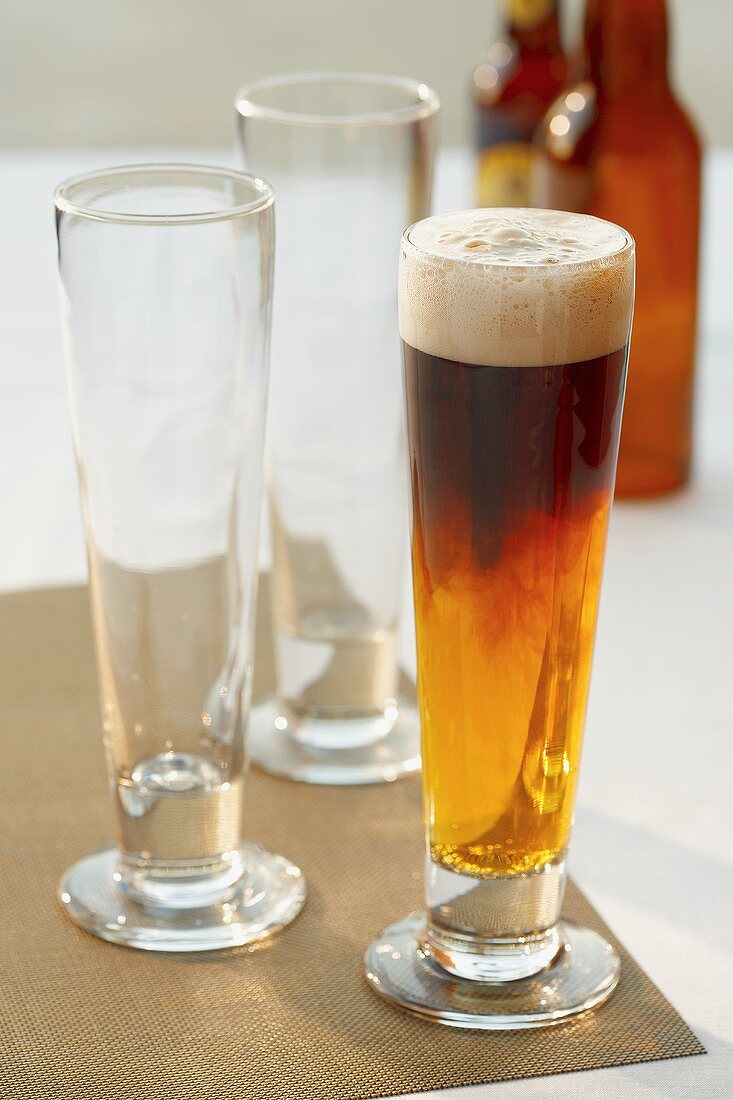 Black and Tan (Biermixgetränk) neben zwei leeren Biergläsern